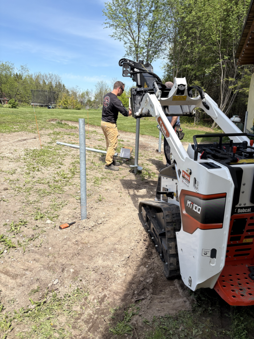Mini skid-steer auger installing metal fence posts