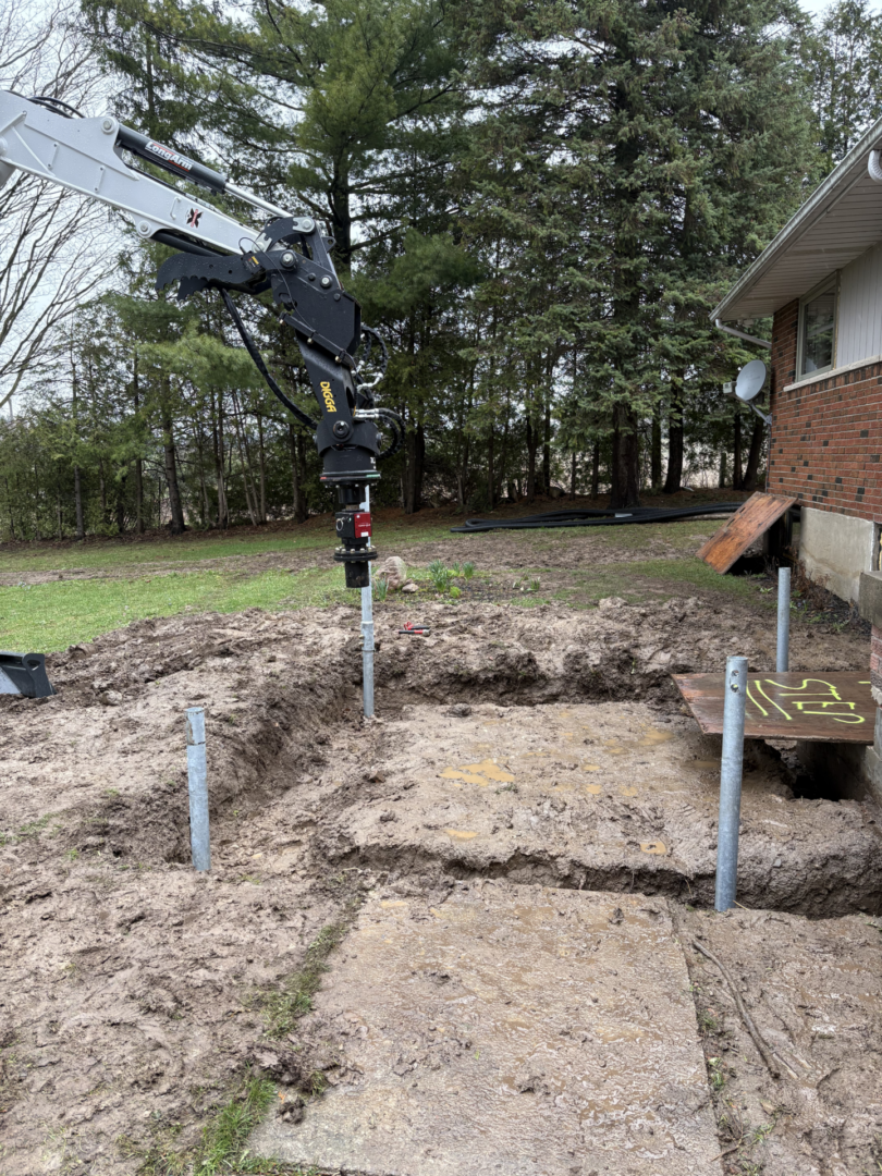 Residential helical pile installation beside brick house