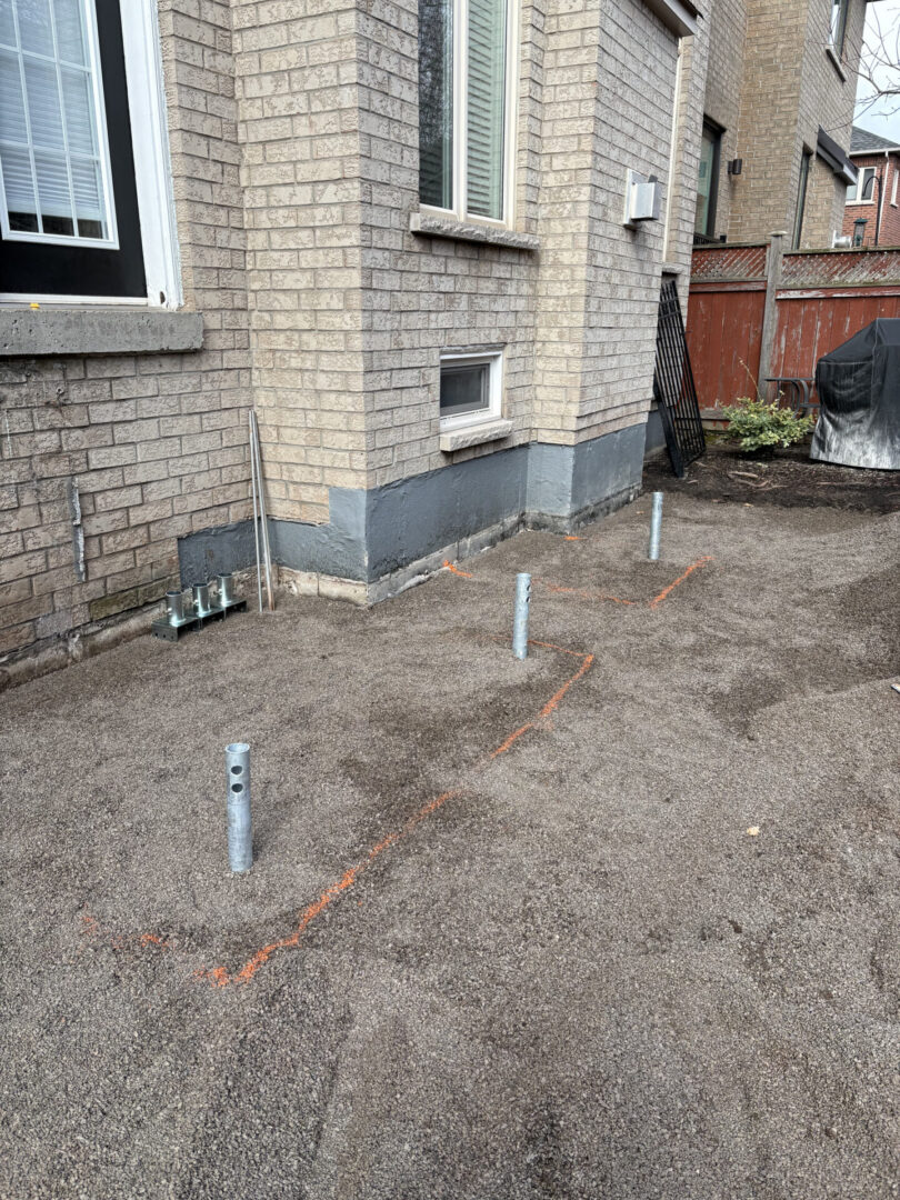 Metal support posts for new deck beside house