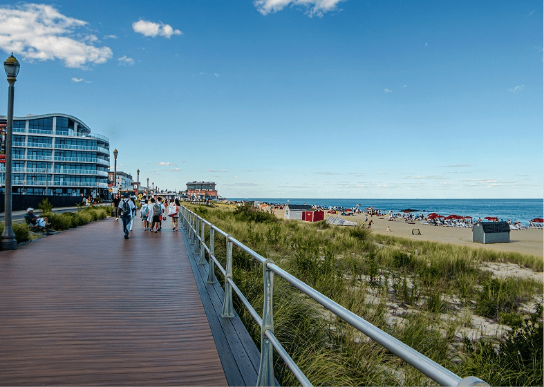 Beach boardwalk with pedestrians, dunes, ocean